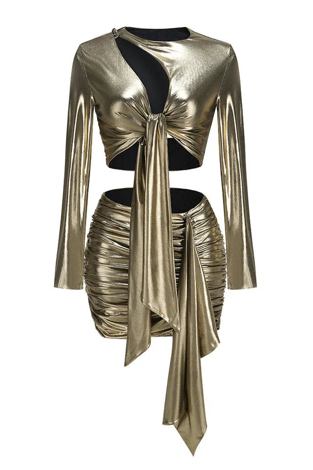 Product shot of a gold metallic two-piece set with a tie-front crop top and ruched mini skirt.
