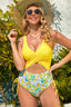 Woman wearing a yellow one-piece swimsuit with a floral print bottom, standing outdoors.