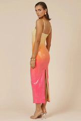 Back view of a model wearing a yellow, orange, and pink ombre sequined midi dress with spaghetti straps and a side slit, against a neutral background.