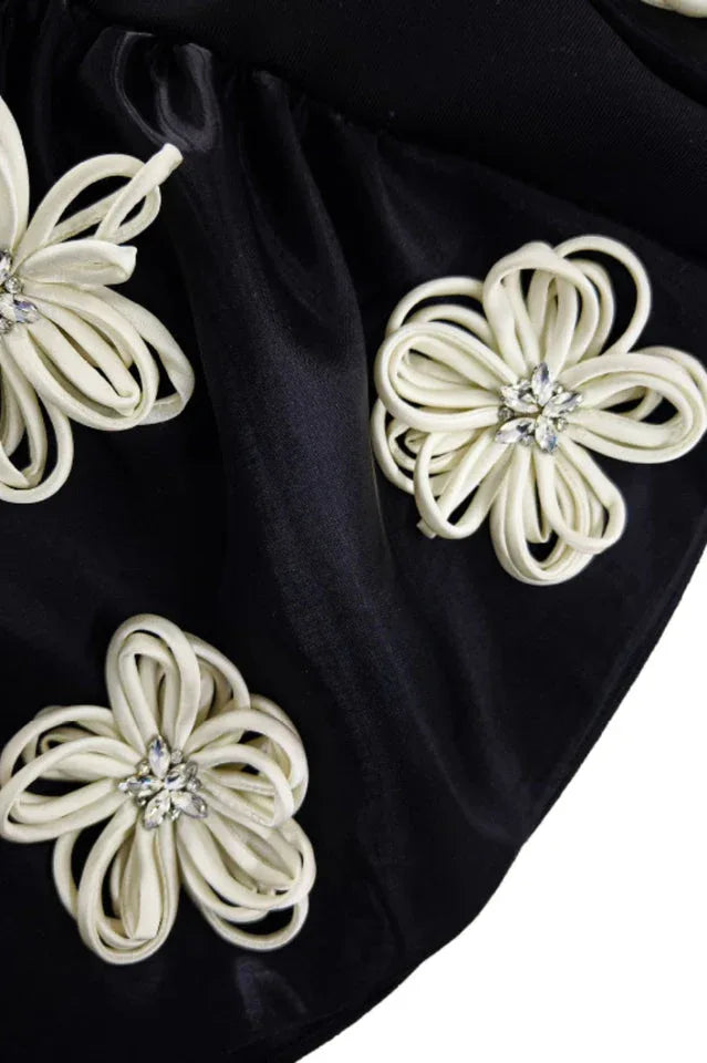 Detailed view of the appliqué floral embellishments on the black dress