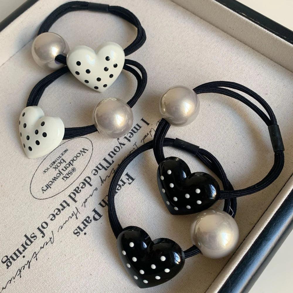 Close-up of heart-shaped hair ties with polka dots and silver beads in a tray