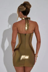 Woman wearing a gold metallic halter dress with a draped cowl neckline, side profile.