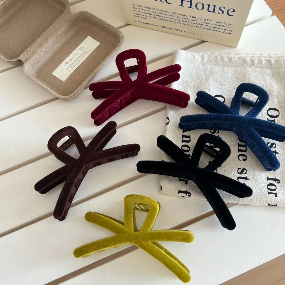 Group of velvet interlocking hair claw clips in different colors arranged on a white table
