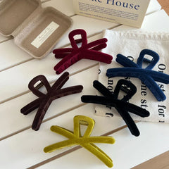 Group of velvet interlocking hair claw clips in different colors arranged on a white table