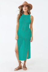 Woman wearing a teal crocheted knit sleeveless maxi dress with a high slit and a wide-brim hat.