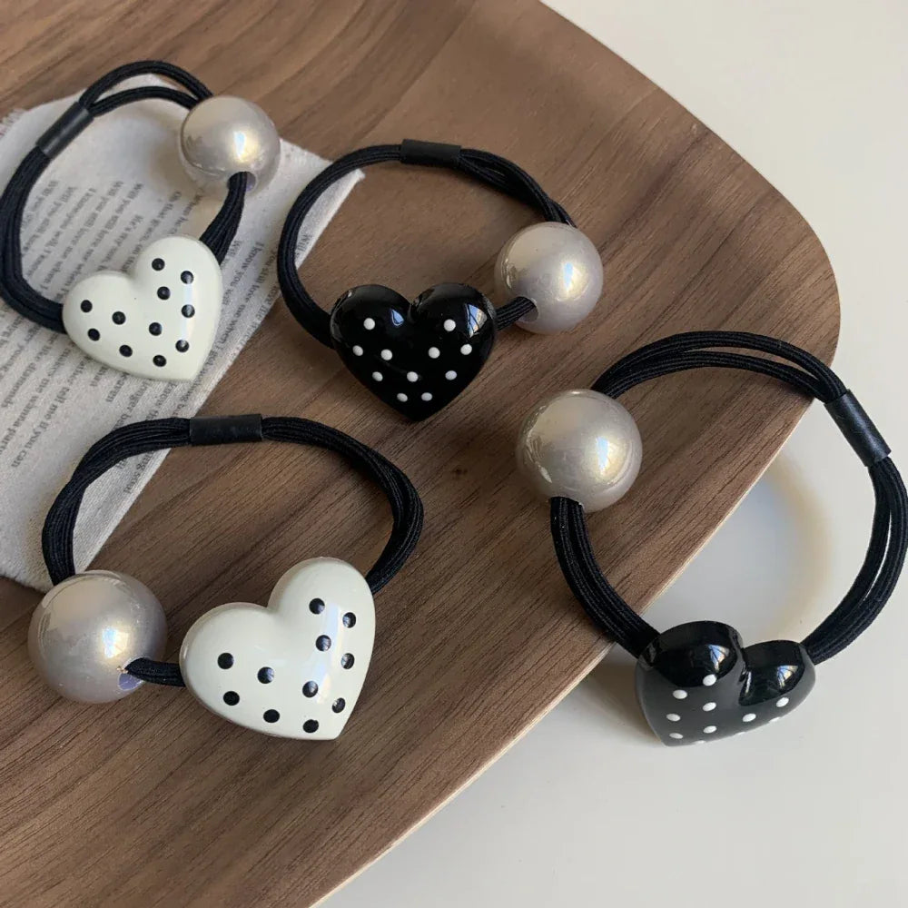 Assortment of heart-shaped hair ties with polka dots and silver beads on a wooden tray
