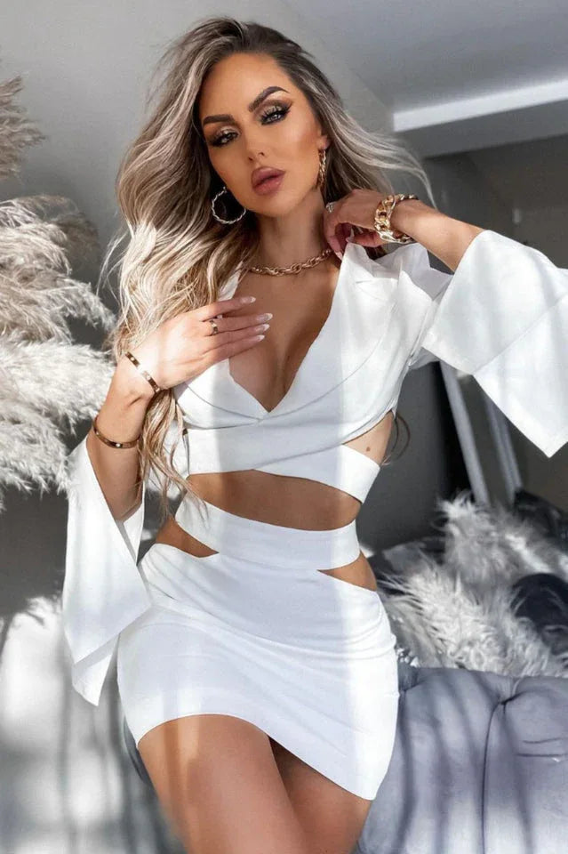 Woman wearing a white two-piece set with cut-out details, deep V-neck, and bell sleeves.