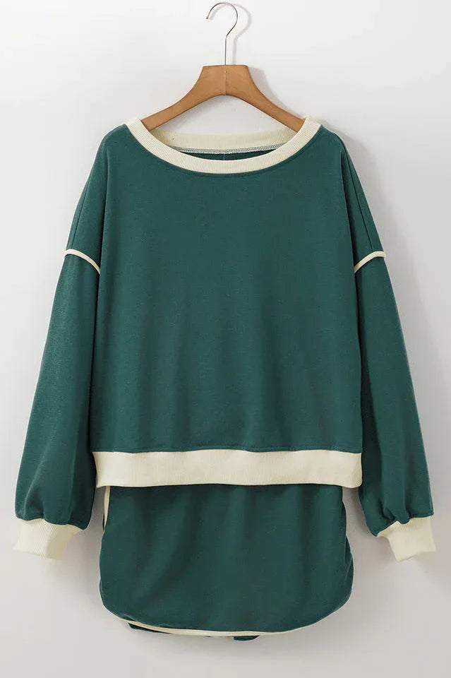 Green crew neck sweatshirt with cream trim hanging on a wooden hanger