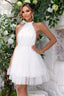 Woman wearing a white halter neck tiered tulle party dress, standing and posing.