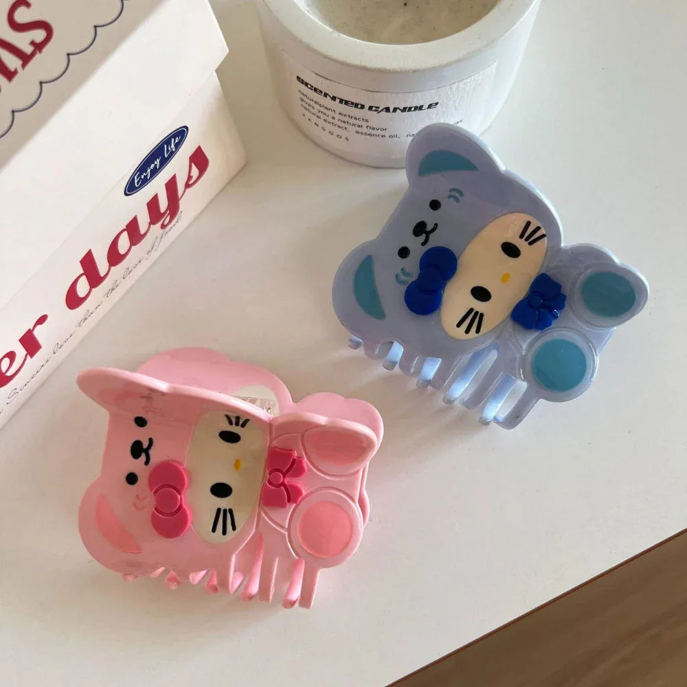 Pair of blue and pink character hair claw clips on a white surface