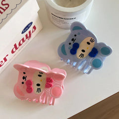 Pair of blue and pink character hair claw clips on a white surface