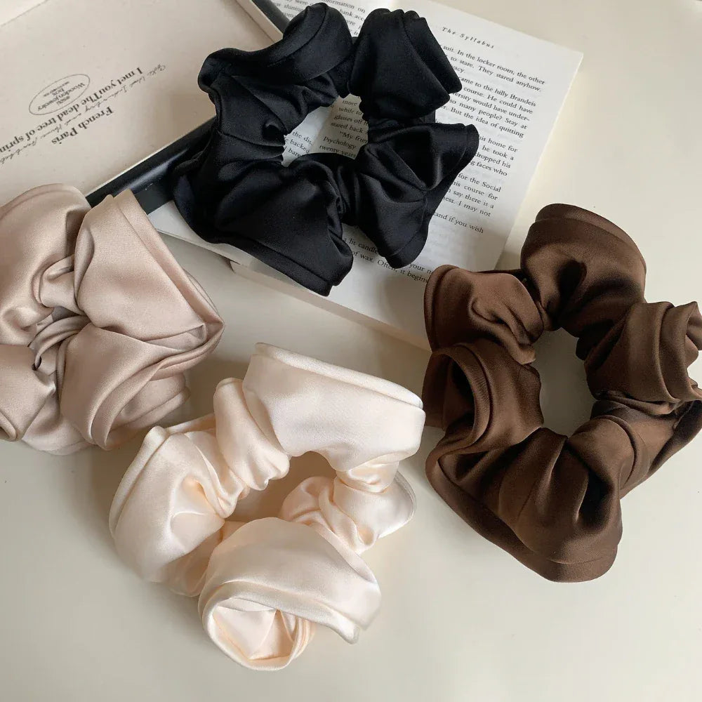 group of scrunchies in brown, black, beige, and cream placed on a book