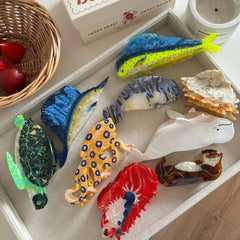 Various animal-shaped hair clips arranged on a tray with fruit and a candle
