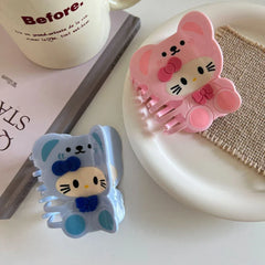 Blue and pink character hair claw clips on a white plate with a book