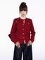 Woman wearing a red cable knit cardigan with a plaid shirt underneath and dark wash wide-leg jeans.