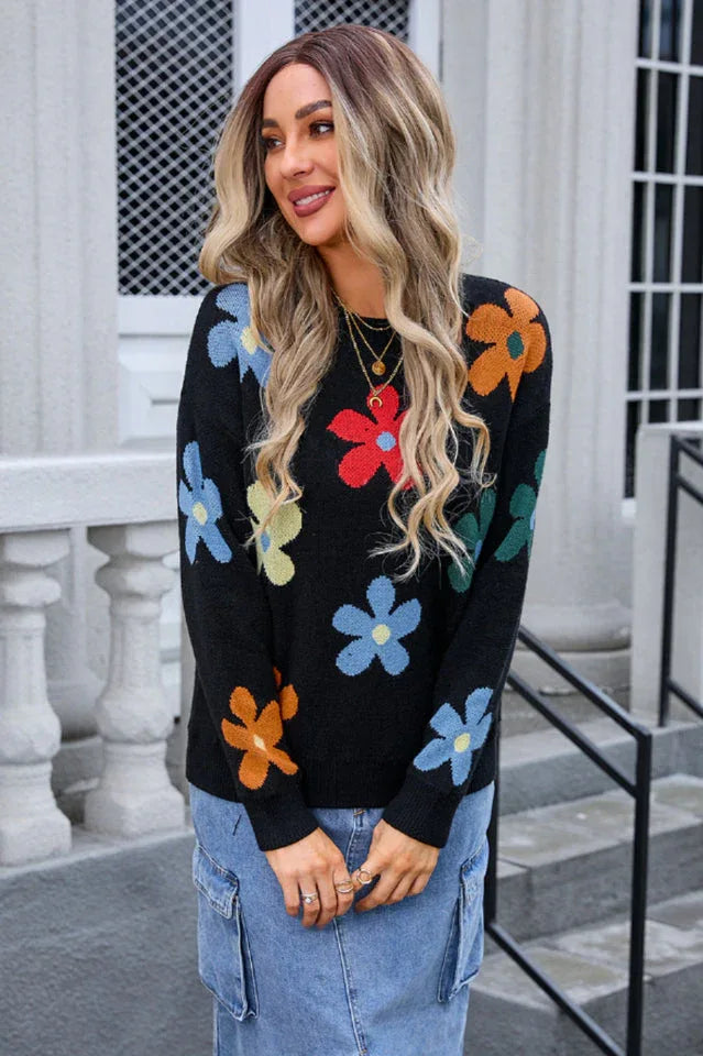 Woman wearing a black long-sleeve sweater with a colorful floral print, paired with a denim skirt.