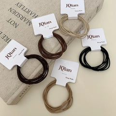 A variety of JQian elastic hair ties in neutral shades, displayed on top of a book.