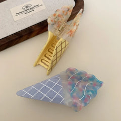 A close-up of two opened ice cream cone hair clips, one blue and one yellow.