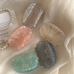Various seashell-shaped hair clips with iridescent finishes and delicate embellishments