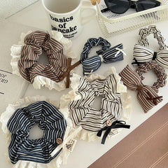 A collection of striped scrunchies with lace trim and bow accents arranged on a white surface.
