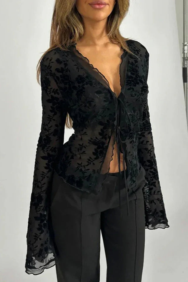 Woman wearing a black floral burnout long-sleeve top with tie-front closure and black pants
