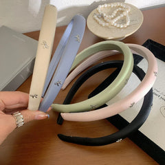 Hand holding a selection of pastel padded headbands with bow charms