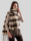 Close-up of a woman wearing an oversized plaid scarf, with her hand gently touching the scarf near her chin.