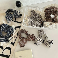 Several striped scrunchies with lace trim and bow accents are displayed with other items on a white surface.