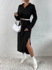 Woman wearing a black long-sleeved ribbed knit dress with a high slit, white boots, a white handbag, and a white belt with gold accents.