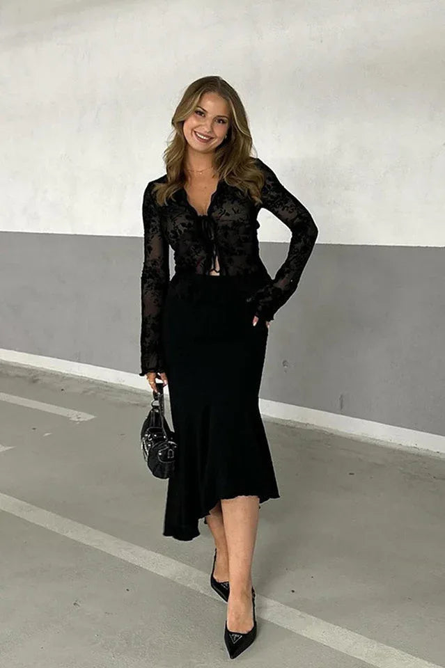 Woman wearing a black floral burnout long-sleeve top with tie-front closure and a black midi skirt