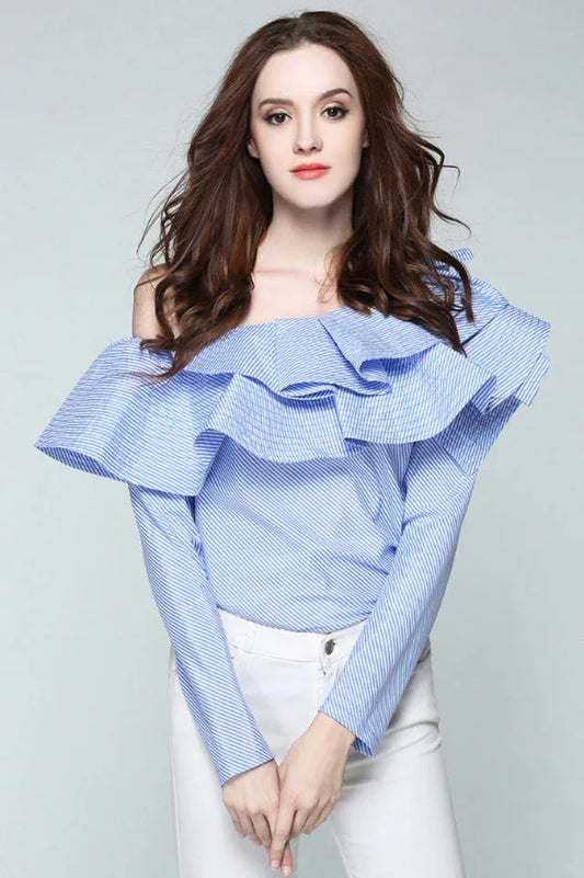 Woman wearing a blue and white striped off-the-shoulder blouse with large ruffles, paired with white pants.