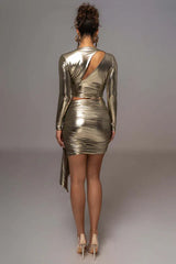 Back view of a woman in a gold metallic two-piece set showcasing an asymmetrical cut-out on the back of the top.