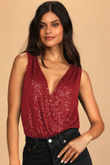 Woman wearing a red sequined sleeveless bodysuit with a deep V-neckline paired with black jeans.