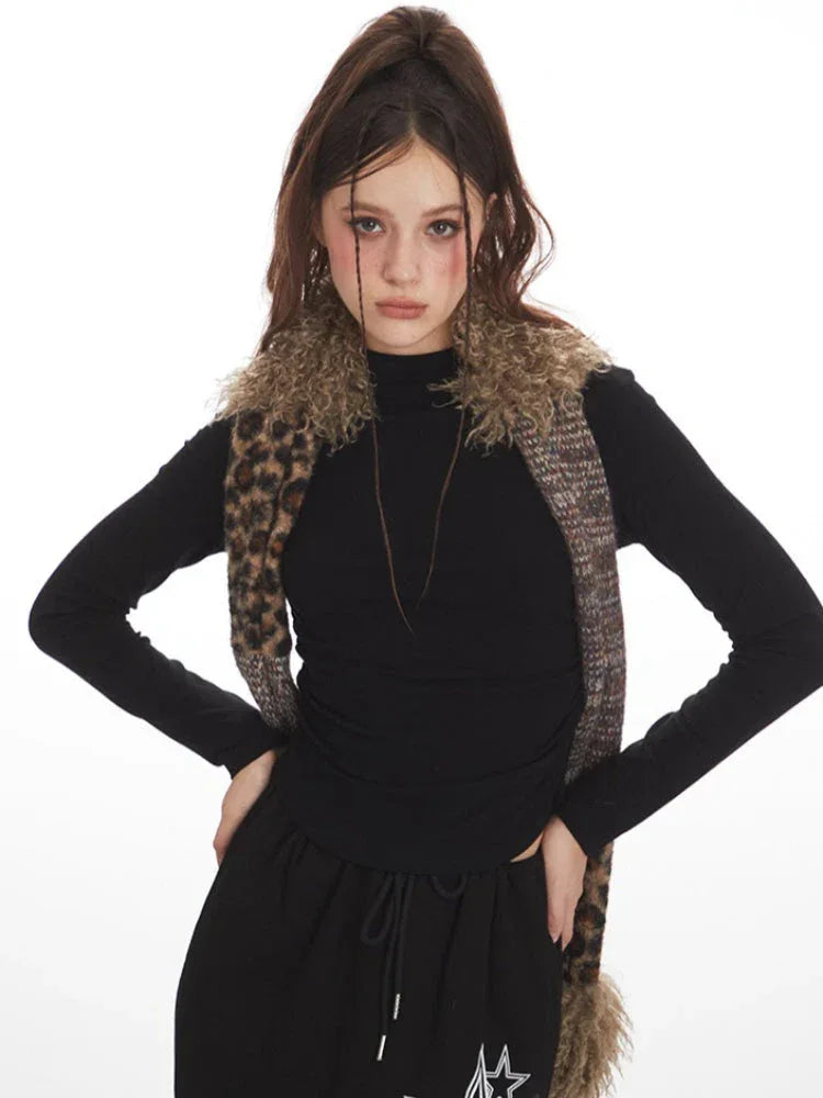 Close-up of a model wearing a black long-sleeve top and a black maxi skirt with a drawstring waist and white star graphics, with a multi-patterned scarf around her neck and hands on hips.