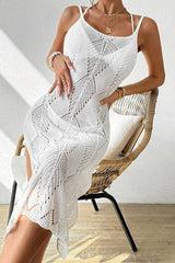 Woman wearing a white knit maxi dress with a high leg slit, sitting in a wicker chair.
