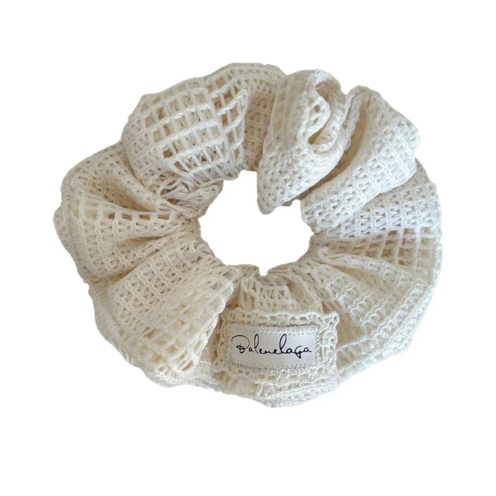 Close-up of a white crocheted scrunchie with a decorative label