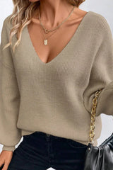 Close-up of a woman wearing a beige V-neck knit sweater with lantern sleeves and black jeans
