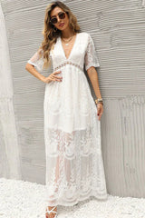 woman in a white lace maxi dress standing against a textured wall