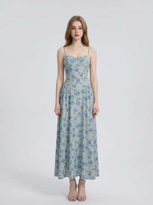 Woman wearing a light blue floral print midi dress with spaghetti straps.