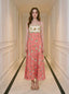 Woman in a coral A-line midi dress with spaghetti straps and a square neckline, standing in a hallway.