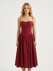 Woman wearing a deep red fit and flare midi dress with spaghetti straps, front view