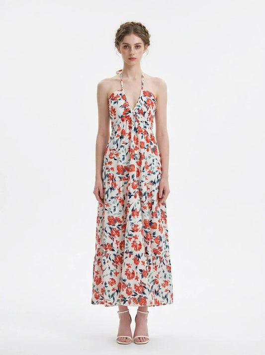 Woman wearing a white floral print maxi dress with a halter neckline and tiered skirt, standing against a white background.