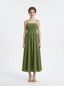 Woman wearing a green linen midi dress with a smocked bodice and square neckline, standing against a white background.