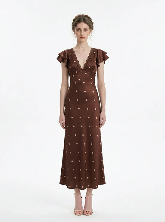 Woman wearing a brown polka dot midi dress with ruffled sleeves and a v-neckline, standing against a white background.