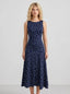 Woman wearing a navy blue sleeveless midi dress with white polka dots, standing and facing forward.