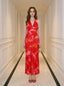 Woman in a red and pink tropical print halter maxi dress standing in a hallway
