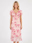 Woman wearing a pink floral print midi dress with short puff sleeves and a tie-front V-neckline, shown from the front.