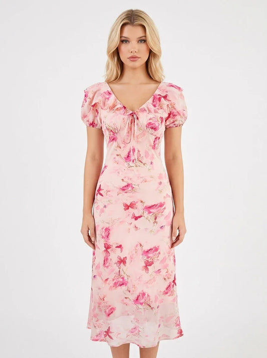 Woman wearing a pink floral print midi dress with short puff sleeves and a tie-front V-neckline, shown from the front.
