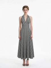 Woman wearing a black and white gingham halter maxi dress, front view