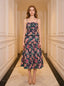 Woman standing in a hallway wearing a navy floral print midi dress with spaghetti straps and a peplum waist.